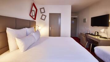 Une chambre d’hôtel avec un grand lit, un bureau, une chaise, une télévision et une porte.