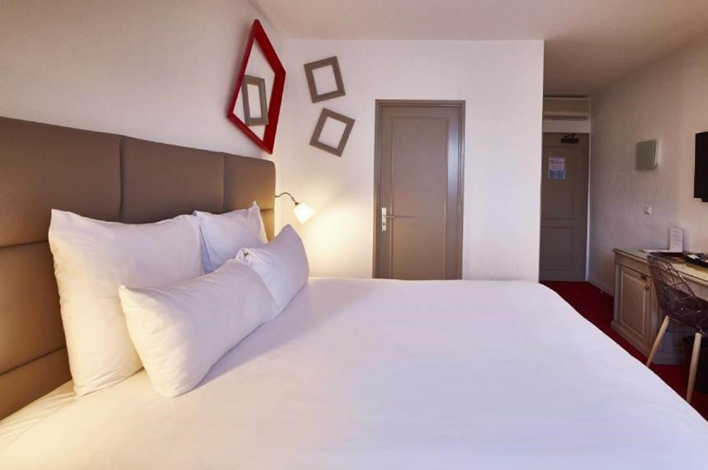 A hotel room with a large bed, a desk, and a door.