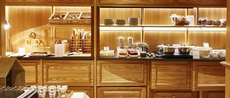 A well-lit breakfast bar with wooden cabinets, a coffee machine, and a variety of breakfast items.