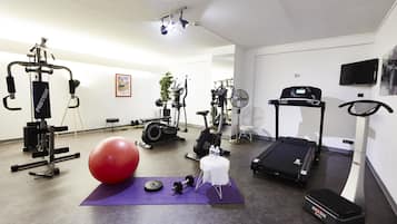 A home gym with exercise equipment, a large red exercise ball, and a treadmill.