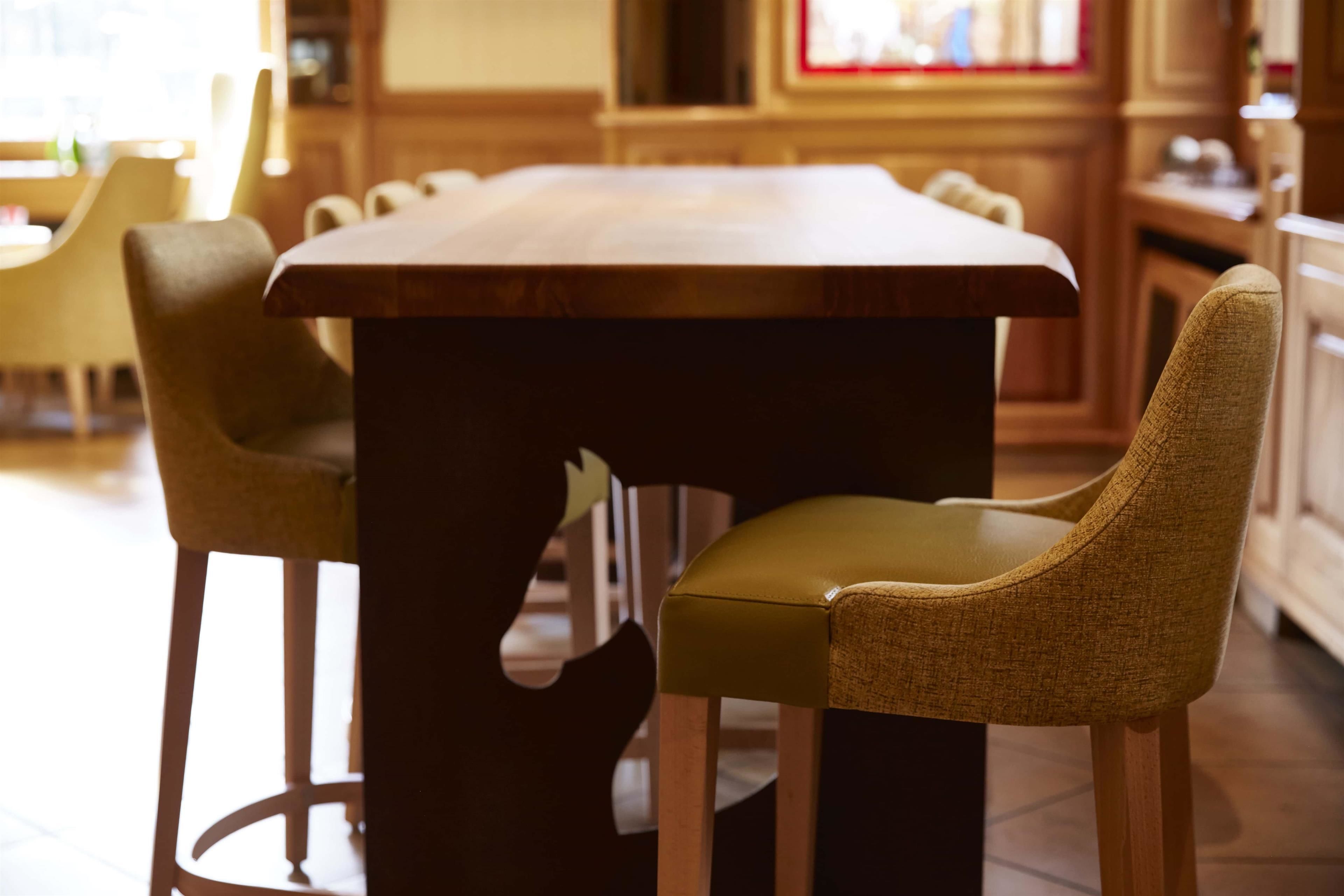 A dining area with a wooden table and two upholstered chairs with a woven texture.