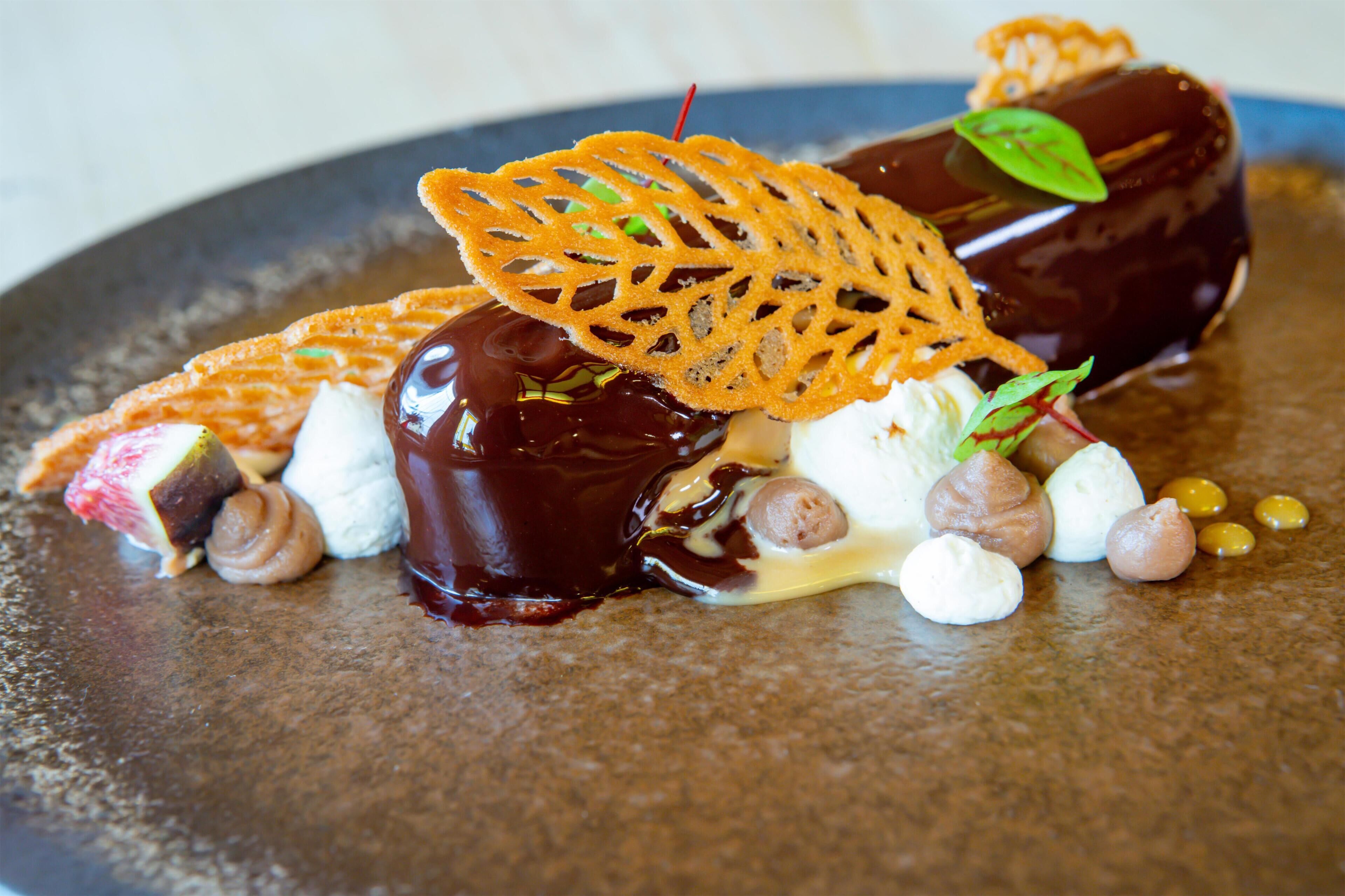 A dessert with various toppings and a chocolate element on a plate.