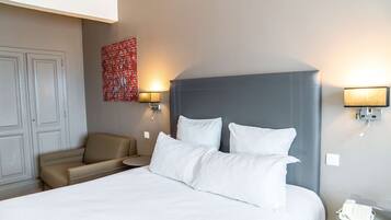 A hotel room with a large bed, a sofa, two wall-mounted lamps, and a telephone on the nightstand.