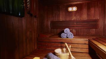 Una sauna de madera con bancos, un banco con una toalla, un cuenco de madera y una cuchara de madera.
