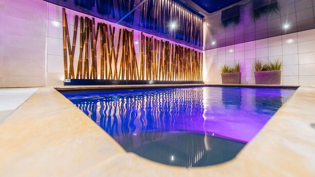 A modern indoor pool with a unique bamboo wall design and a clear pool bottom. - Best Western Plus Au Cheval Blanc Mulhouse Nord (Baldersheim)