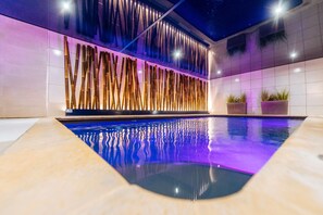 A modern indoor pool with a unique bamboo wall design and a clear pool bottom.