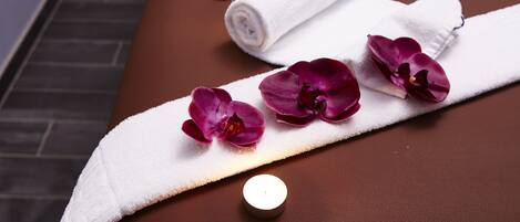 A massage table with candles, towels, and flowers.