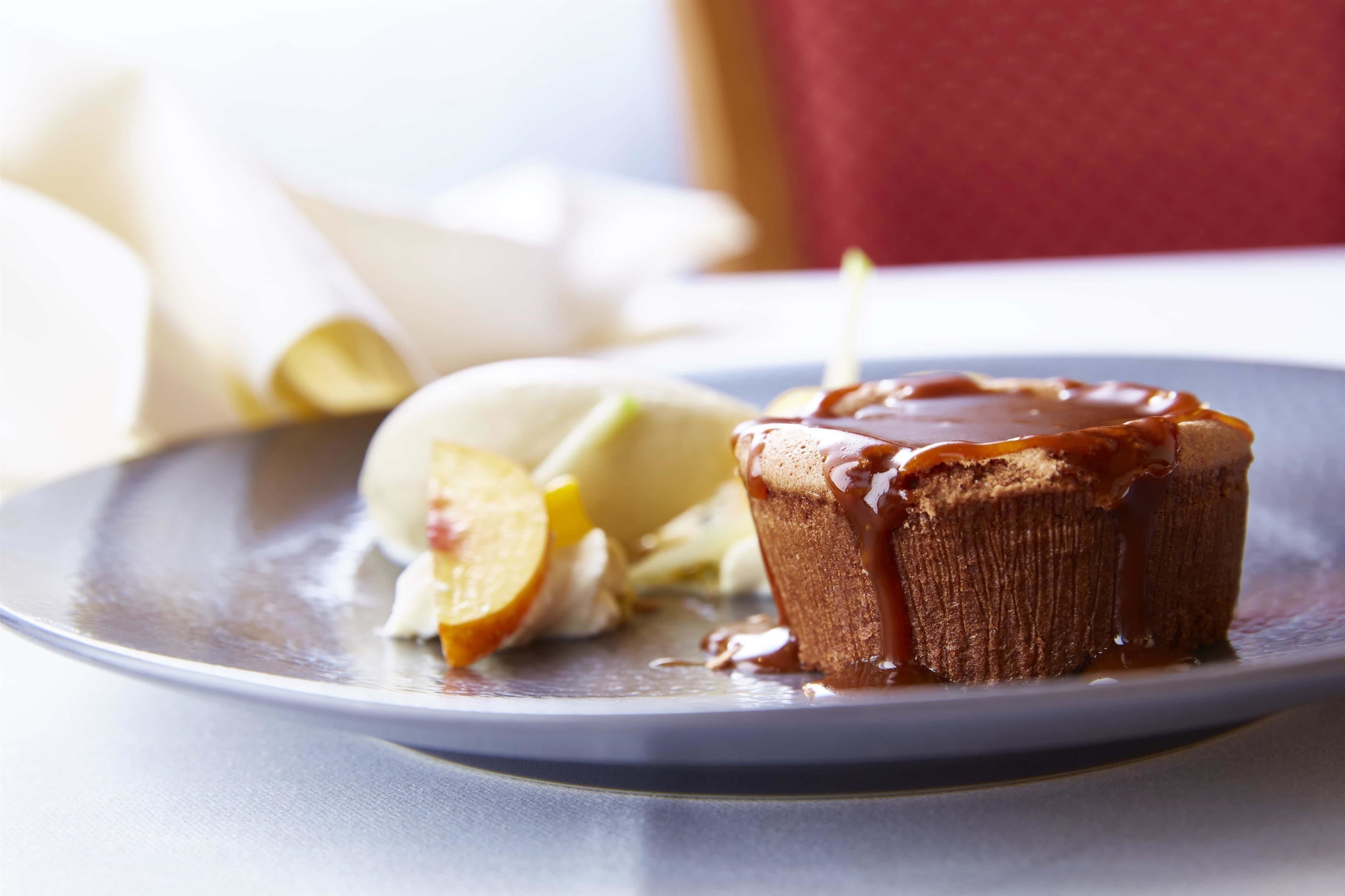 Ein Dessertteller mit einem Karamellkuchen, einer Kugel Eis und Apfelscheiben.