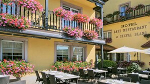 A hotel cafe restaurant with outdoor seating and flower boxes on the balconies. - Best Western Plus Au Cheval Blanc Mulhouse Nord (Baldersheim)