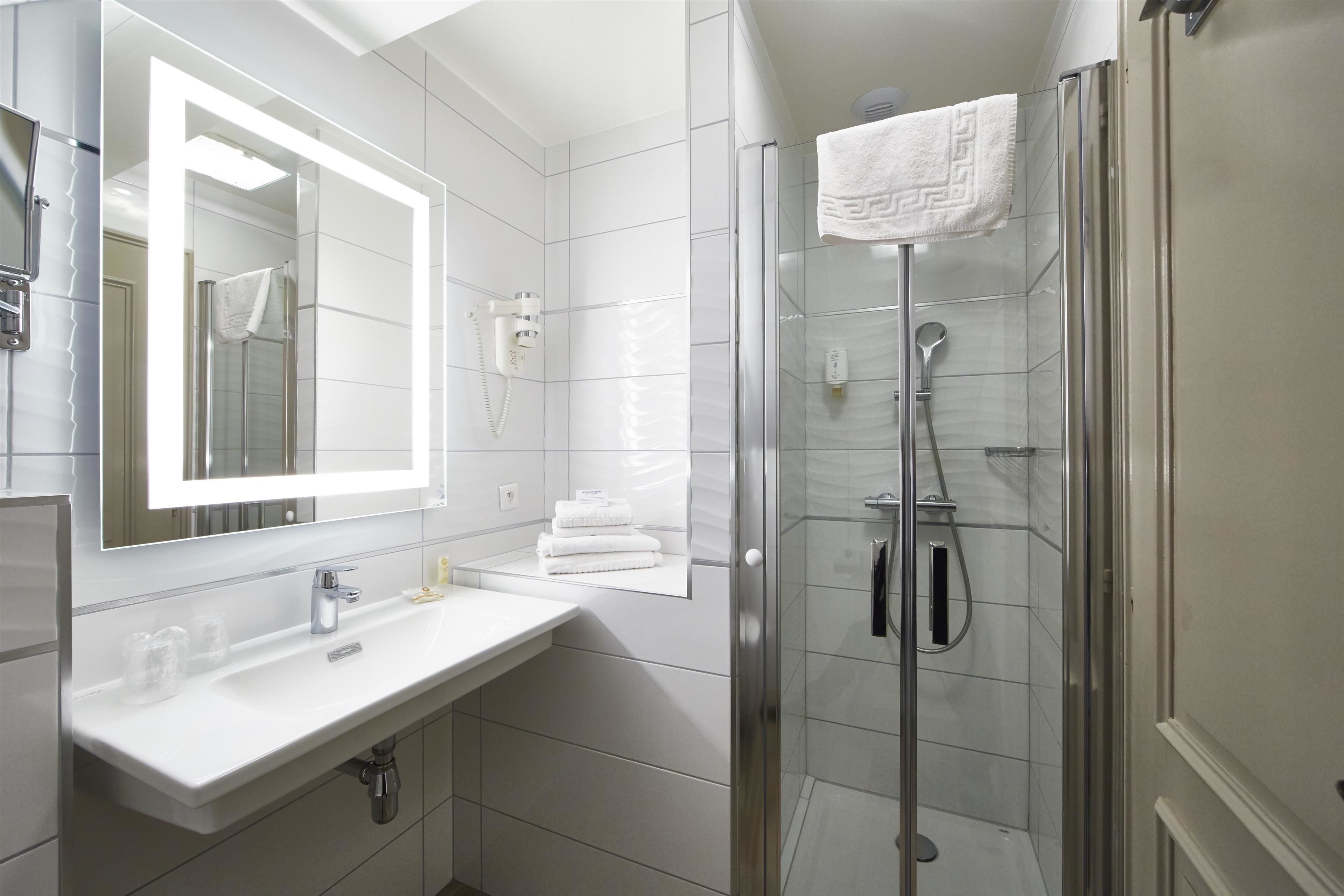 Un bagno moderno con un lavandino bianco, uno specchio grande e una cabina doccia in vetro.