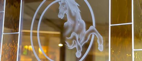 Una ventana de vidrio con la silueta de un caballo blanco dentro de un diseño circular.