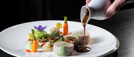 Une assiette blanche contenant divers aliments, notamment une tarte verte, une tranche de viande avec une garniture verte et un petit morceau de carotte.