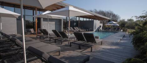 A modern outdoor pool area with lounge chairs and umbrellas.