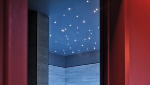 Une salle de bain moderne avec un plafond étoilé et une personne dans une baignoire.