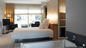 Une chambre d’hôtel moderne équipée d’un grand lit, d’une télévision, d’un bureau et d’une baignoire.