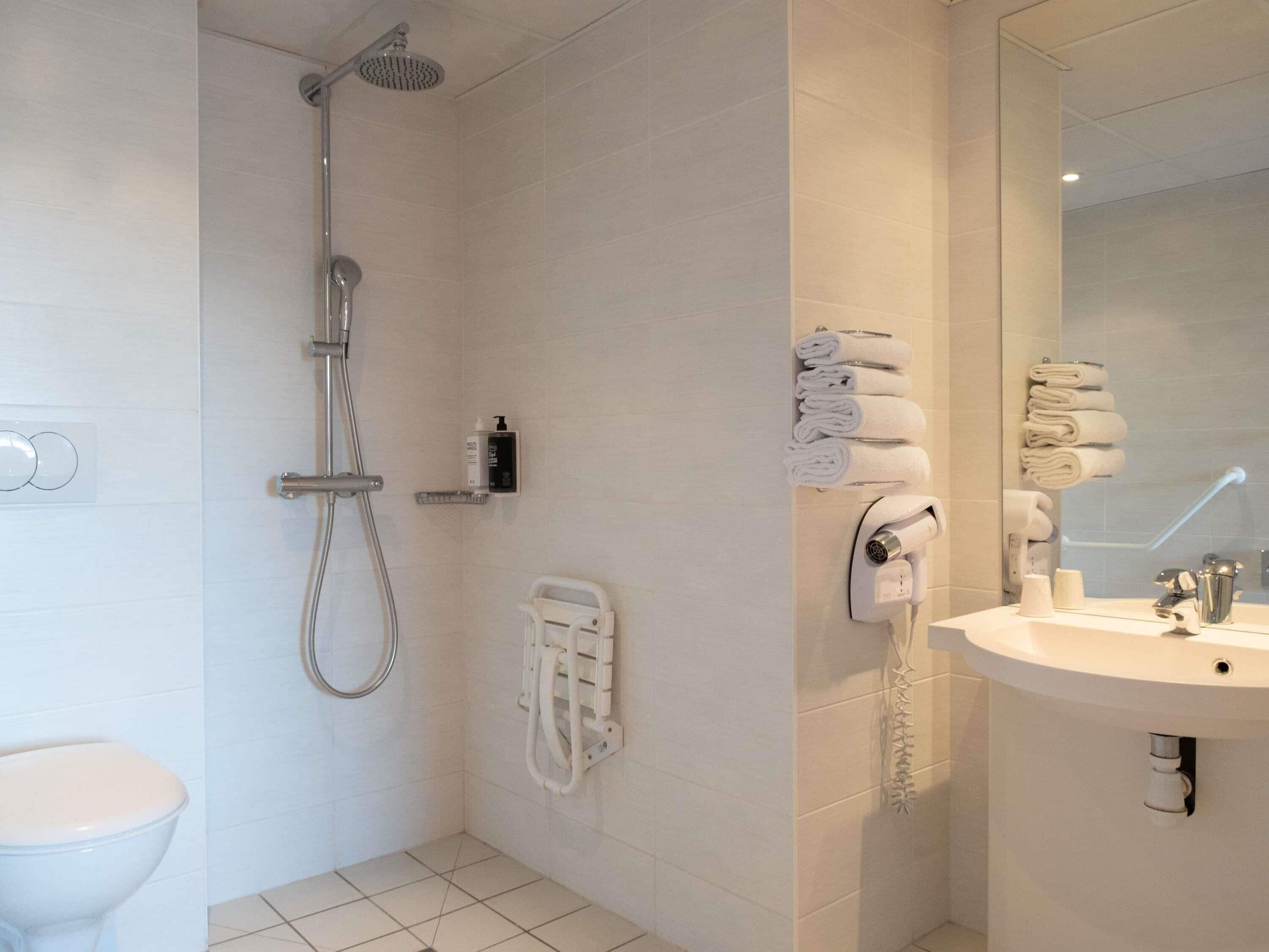 A modern bathroom with a shower, toilet, and sink.