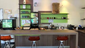 A bar area with a counter, stools, and shelves with various items.