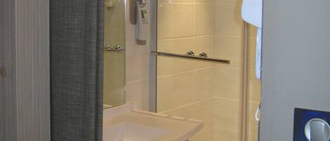 Un baño moderno con cabina de ducha de vidrio, un lavamanos blanco y un perchero para toallas.