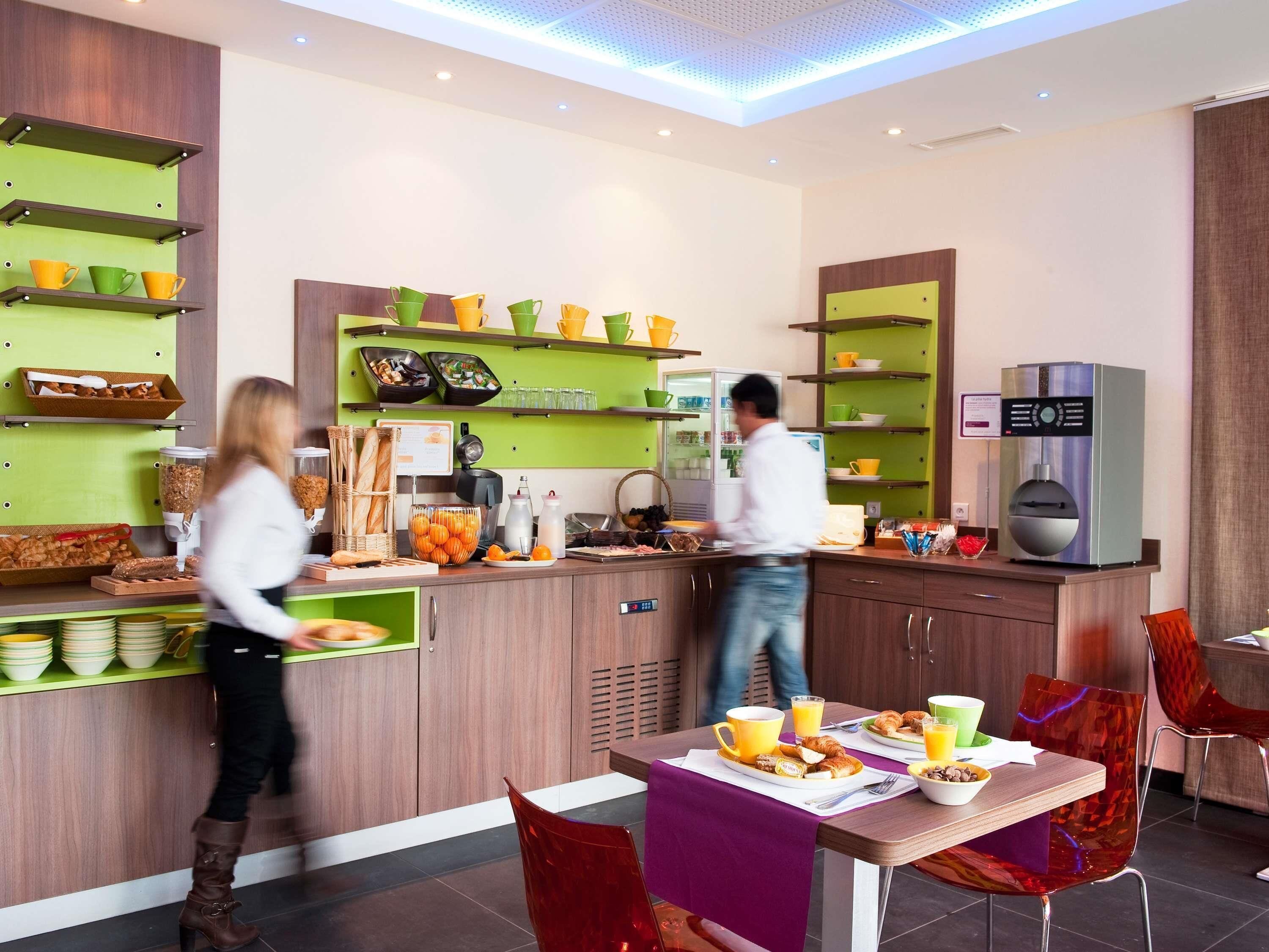 Une cuisine moderne équipée d’un buffet, d’une machine à café et d’un coin repas avec une table et des chaises.