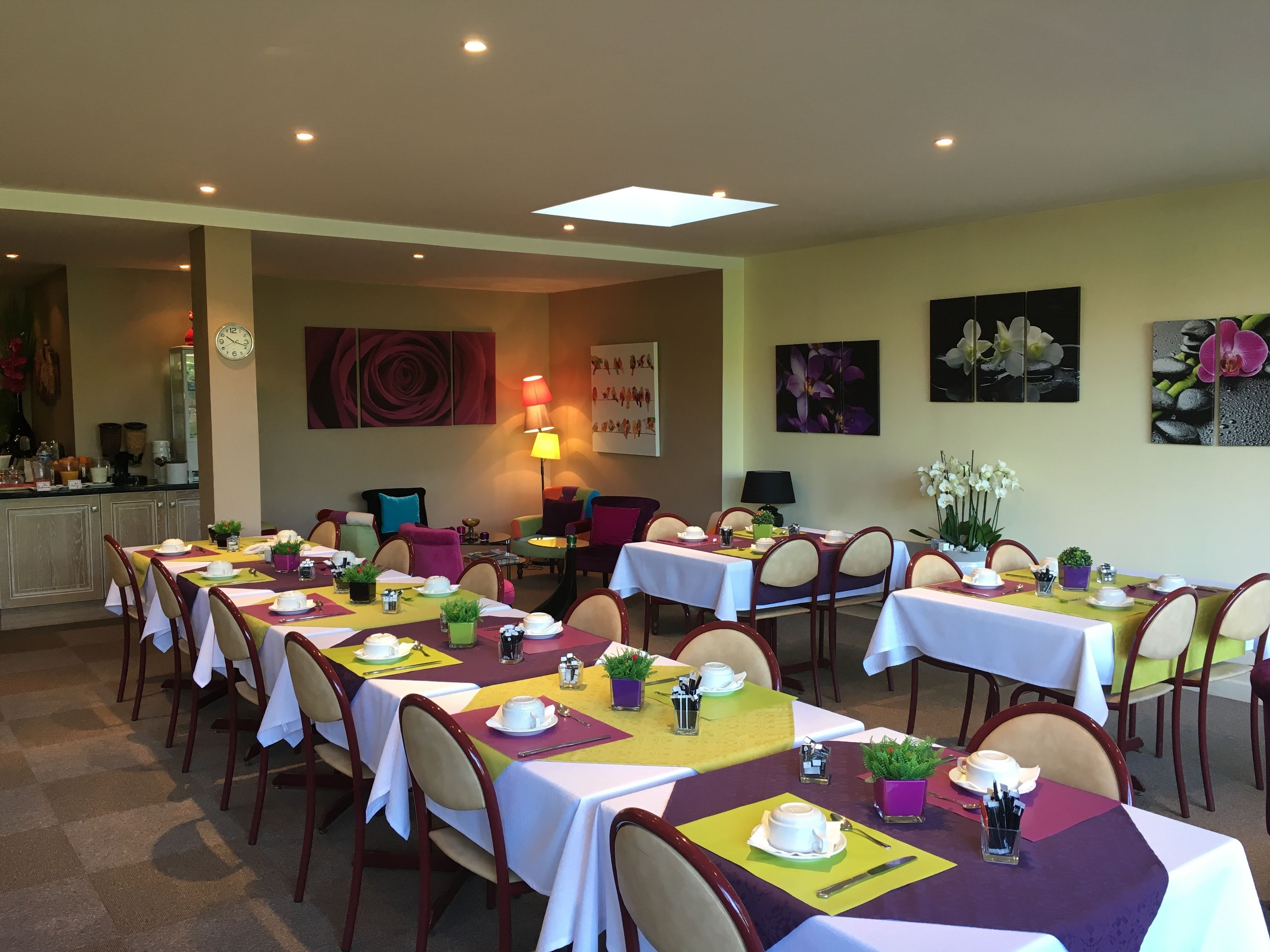 A dining area with multiple tables set for meals, chairs, and a clock on the wall.