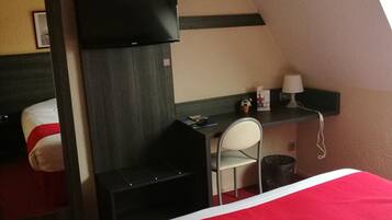 Habitación de hotel con una cama grande, un escritorio con silla, televisión y una mesita de noche con lámpara.