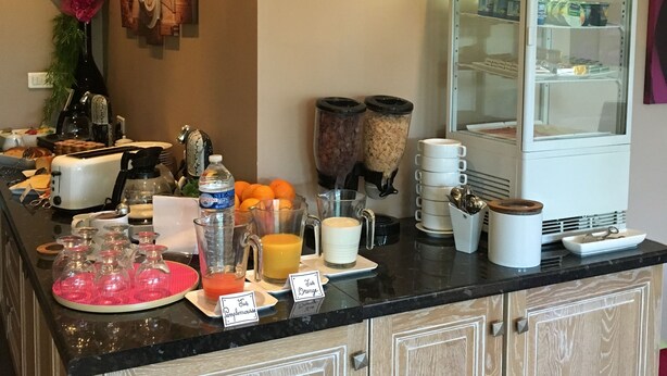 Una cocina con un refrigerador, licuadora y diversos alimentos sobre la encimera.