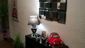 Una consola negra con una lámpara, un coche de juguete rojo y pequeñas macetas.