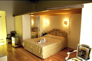 Une chambre à coucher avec un lit, une table de chevet, une chaise et un miroir.