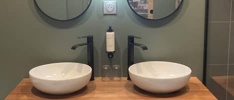 A bathroom with two white sinks, a mirror, and a soap dispenser.