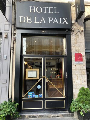 A hotel entrance with a black facade, double doors, and a sign reading 'HOTEL DE LA PAIX'. - Hotel de la Paix Lille (Lille)