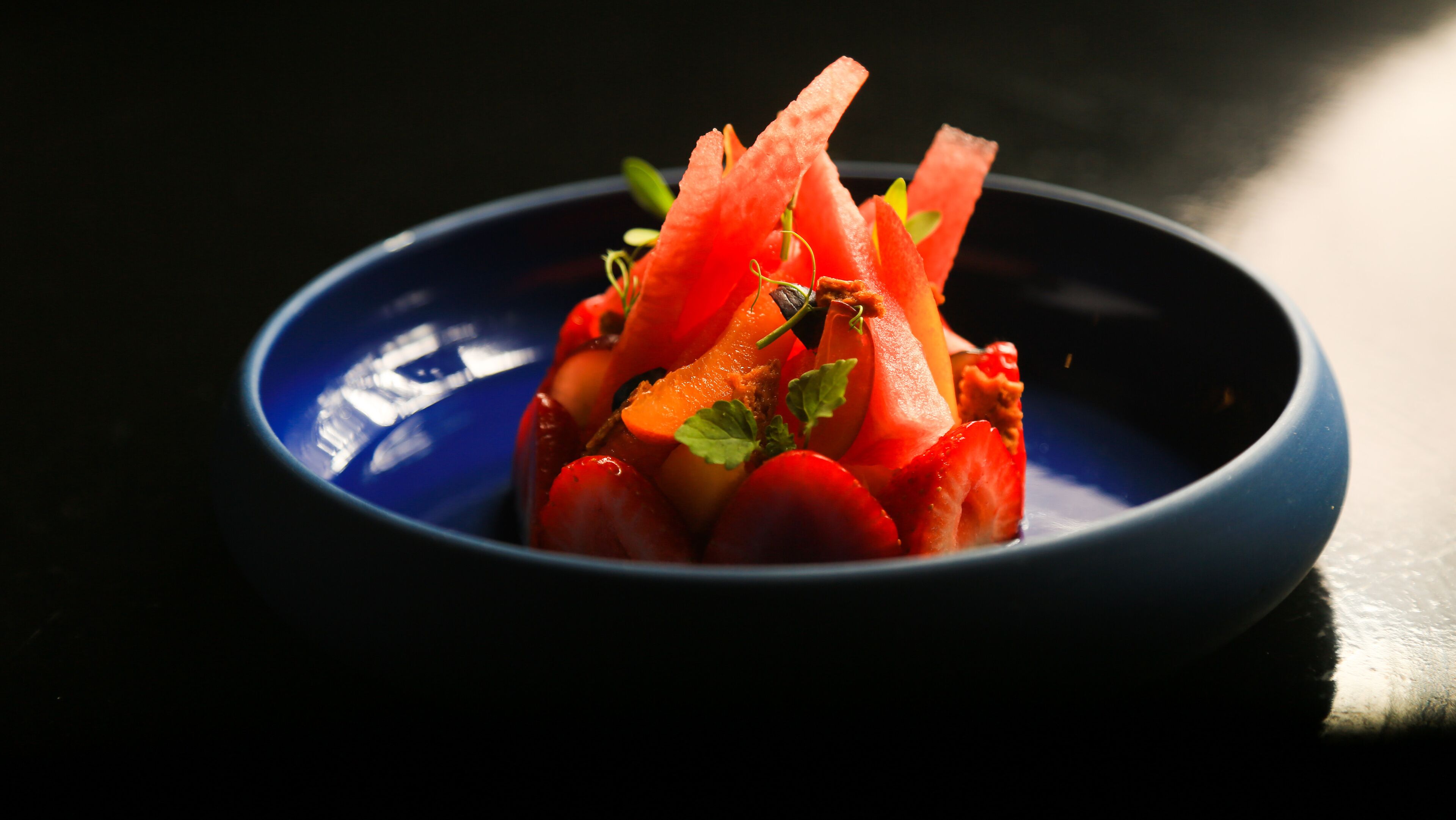 A bowl of watermelon and carrot salad with mint garnish.