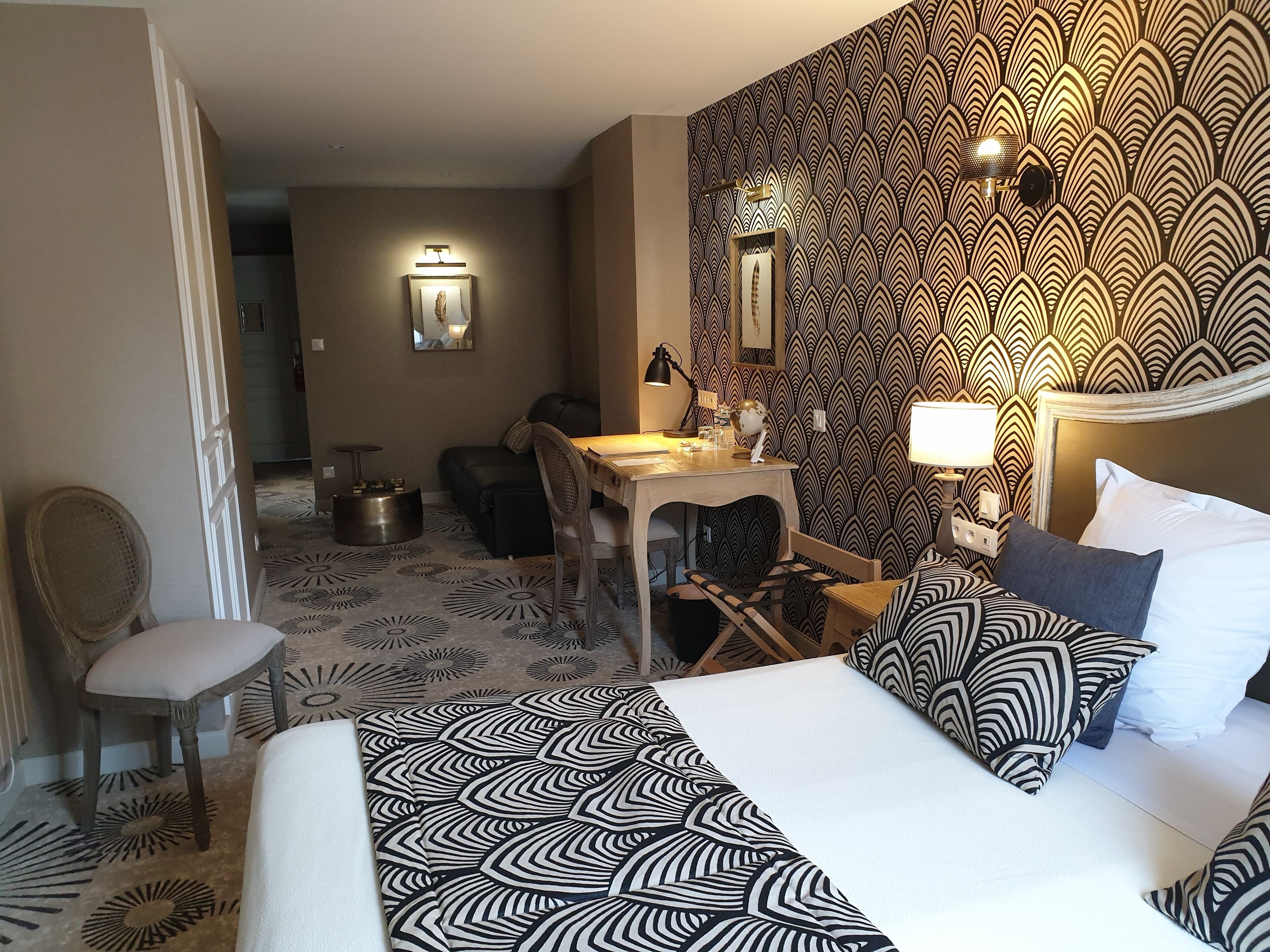 A hotel room with a bed, a desk, a chair, and a dining table.