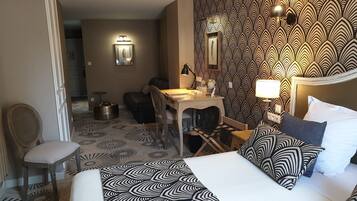 A hotel room with a bed, a desk, a chair, and a dining table.