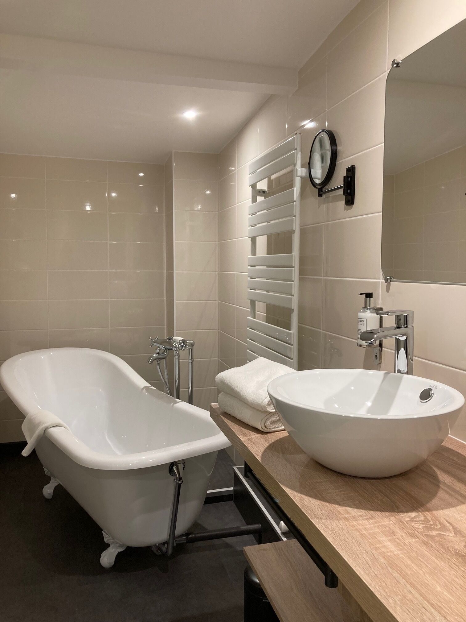 A modern bathroom with a freestanding bathtub, a vanity with a large sink, and a wall-mounted towel rack.