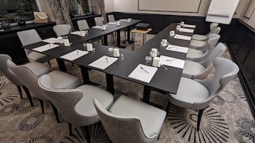 Un salón de conferencias con una larga mesa, varias sillas y una pizarra.
