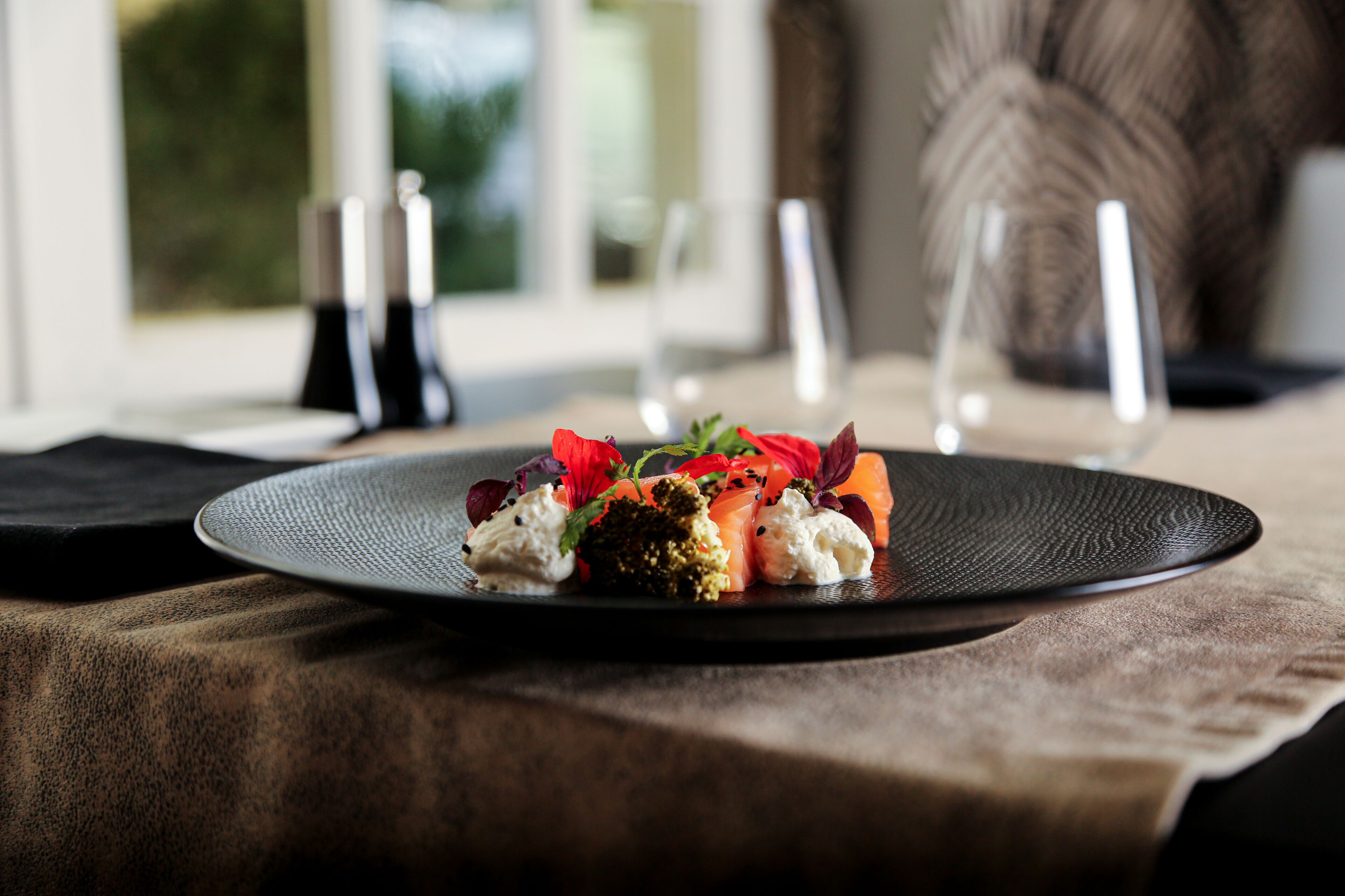 Un plato de comida sobre una mesa, con vistas a una ventana al fondo.
