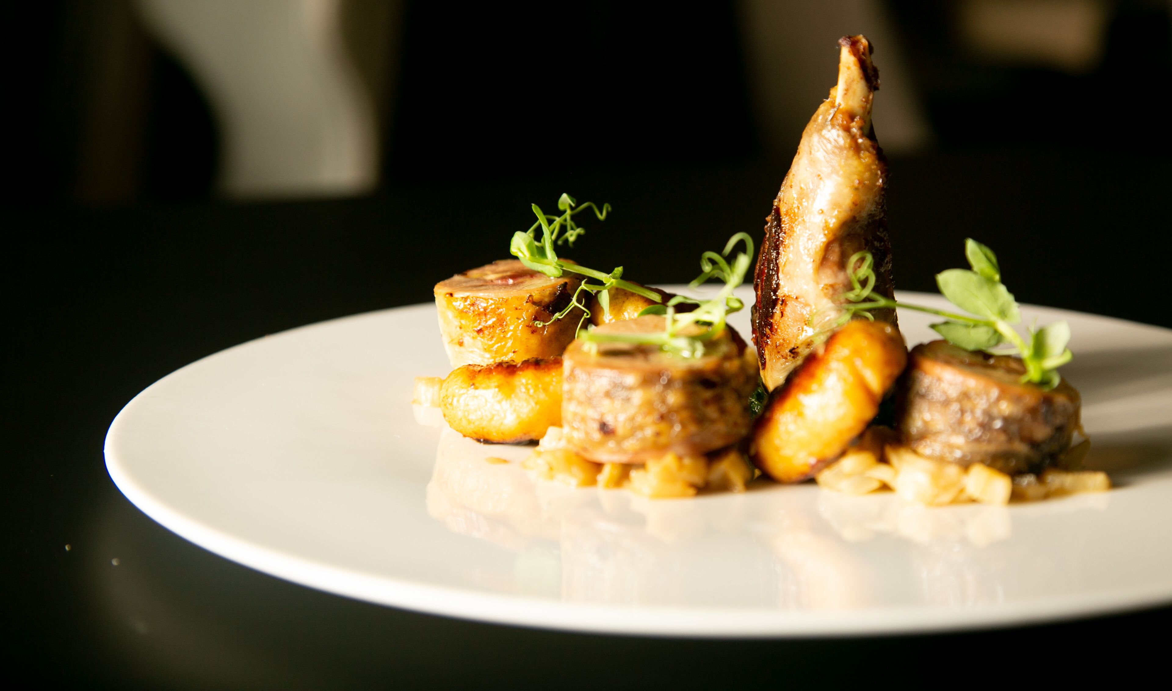 Un plato con pato asado, papas y vegetales verdes.