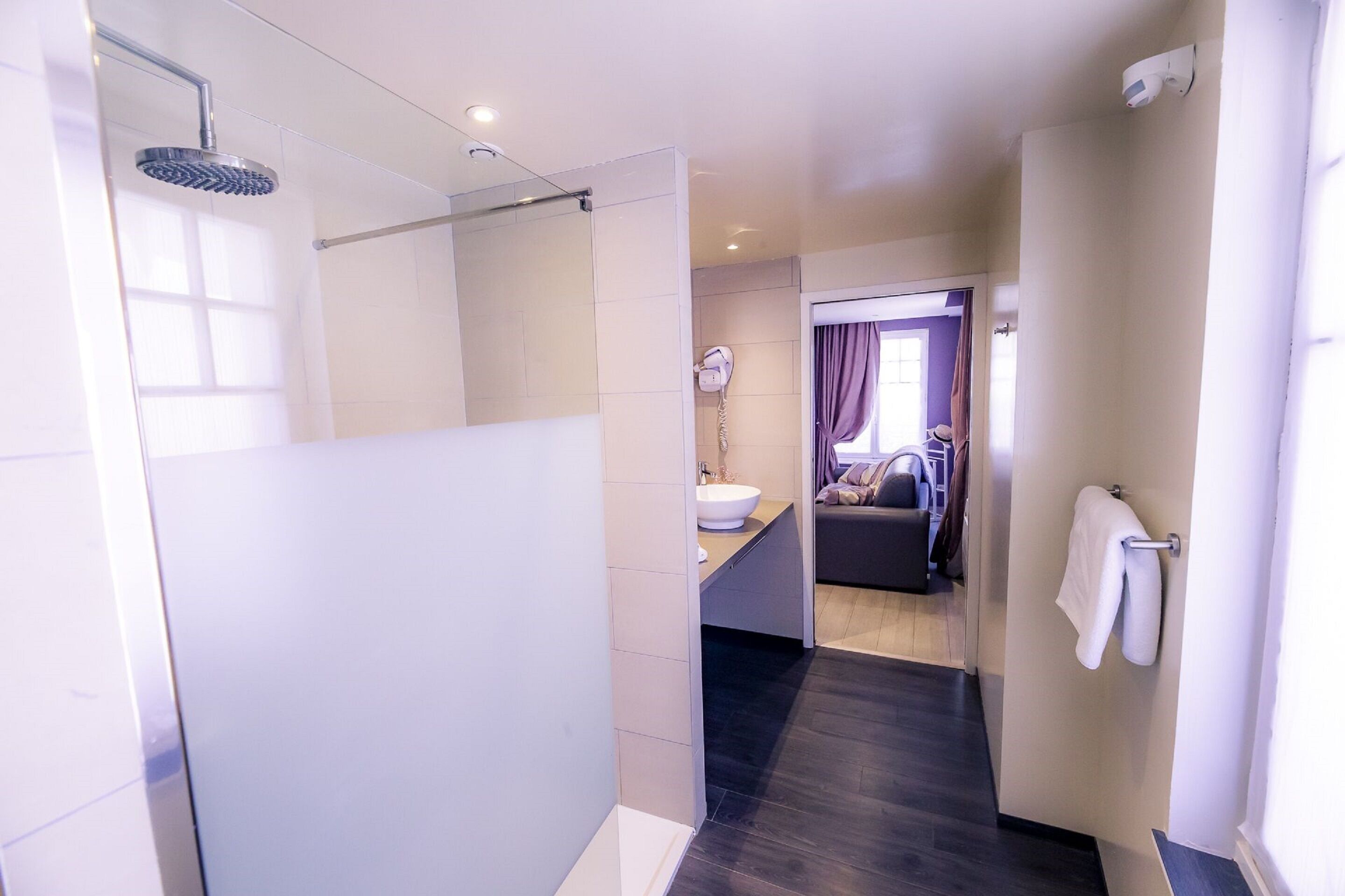A modern bathroom with a glass shower enclosure, a sink, and a towel rack.
