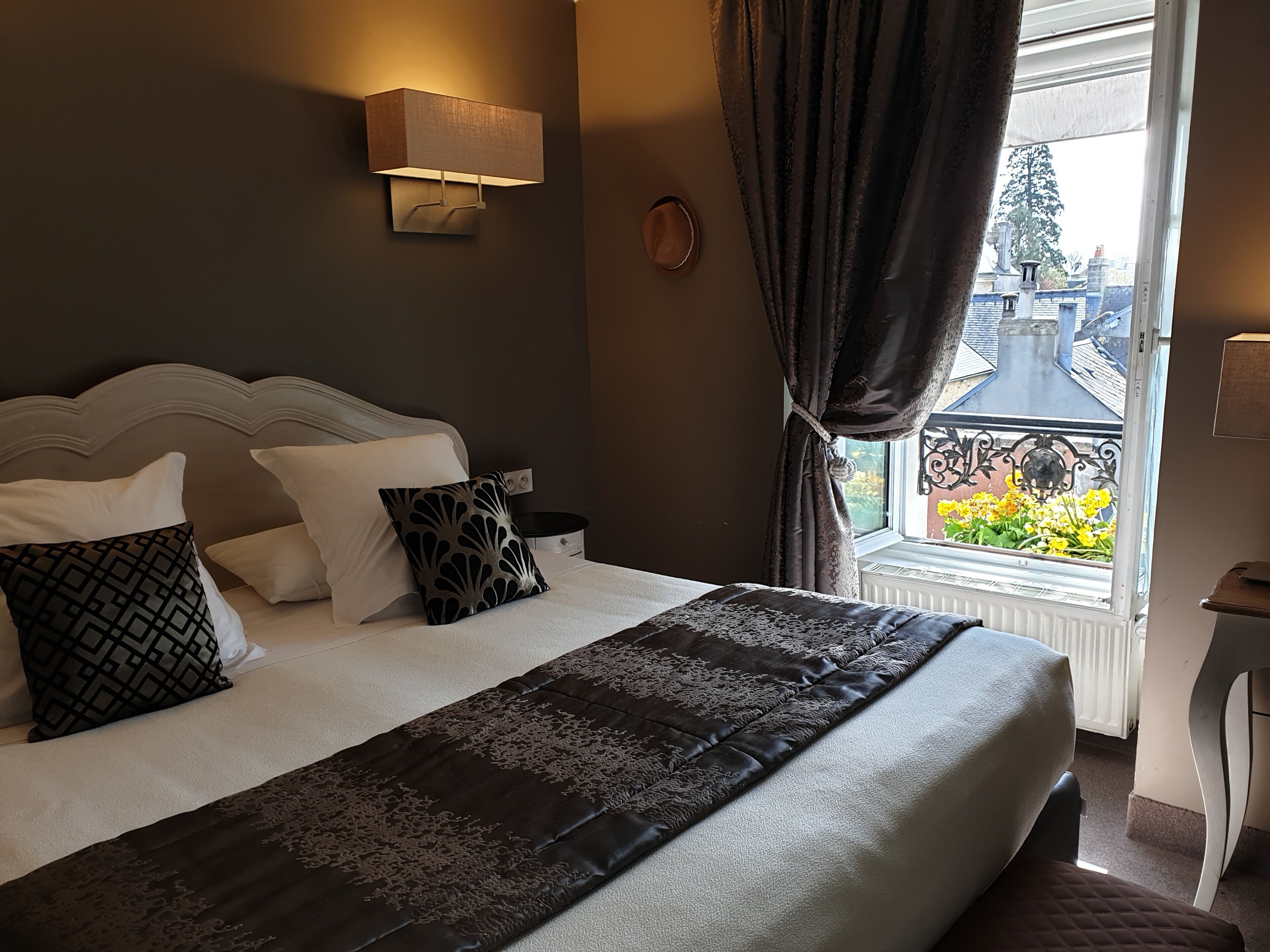 A bedroom with a bed, a bedside table, a lamp, and a window with curtains.