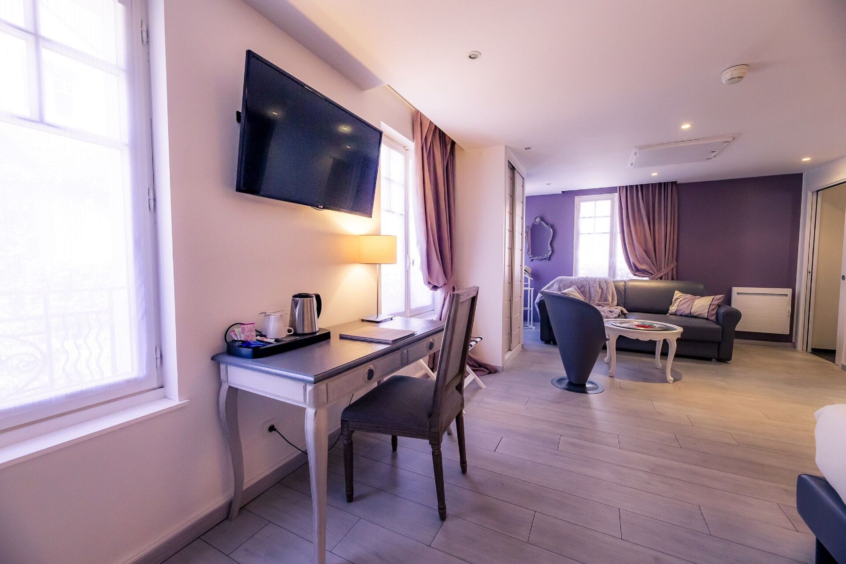 Una habitación de hotel moderna con escritorio, silla, televisor de pantalla plana y sofá.