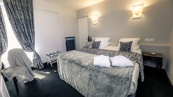 A bedroom with a large bed, a chair, a bedside table, and a wall-mounted light fixture.