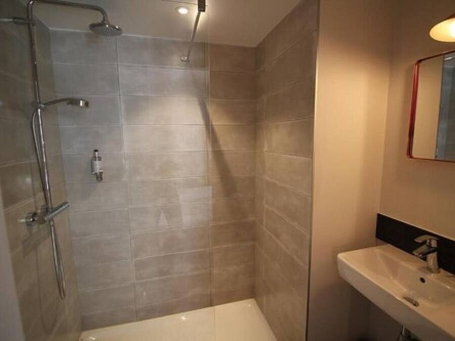 Un baño moderno con ducha, lavamanos y espejo.