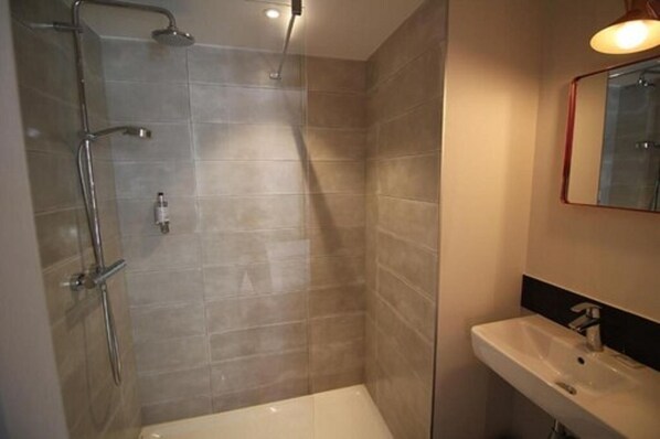 Un baño moderno con ducha, lavamanos y espejo.