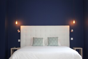 A bedroom with a large bed, two bedside tables, and a headboard with a geometric pattern. - Hôtel La Fontaine Caen Centre (Caen)