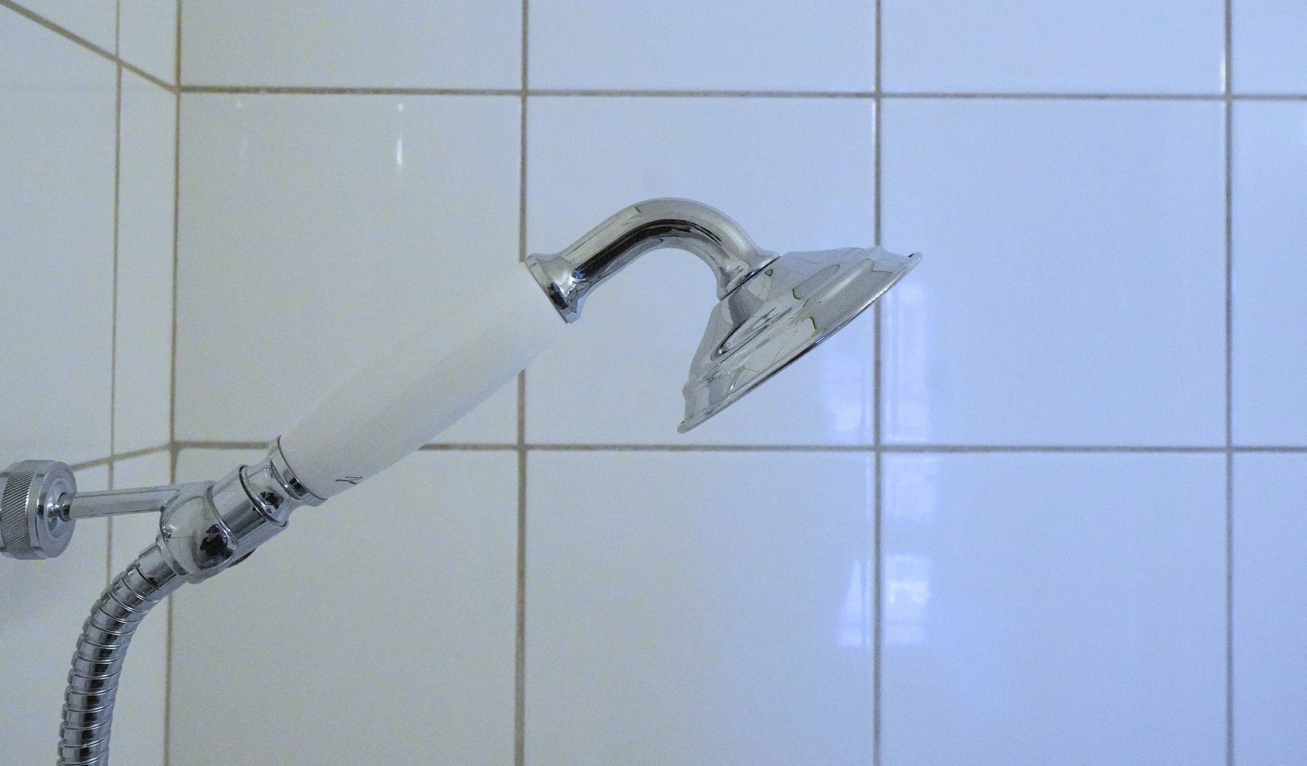 Ducha con cabezal de ducha cromado y grifo blanco.