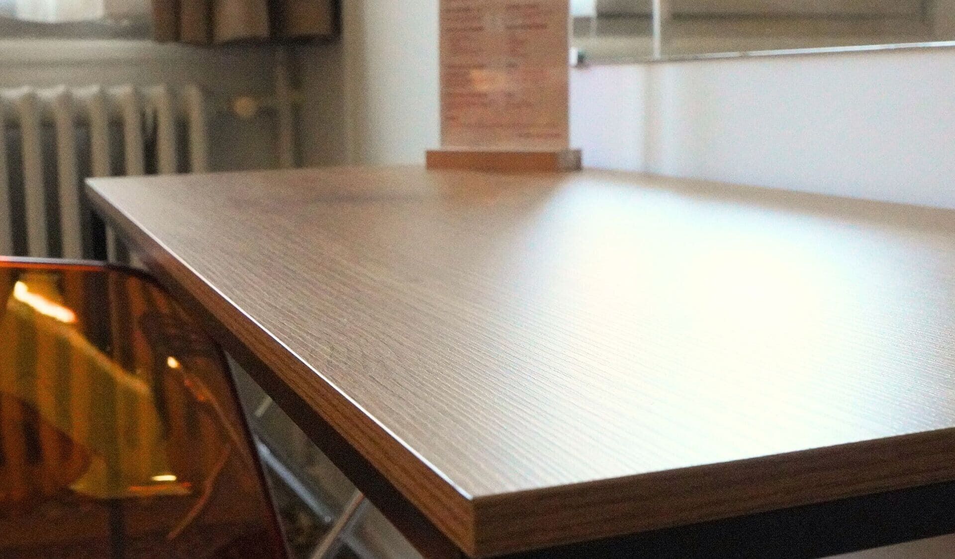 A wooden table in a room with a radiator and a window in the background.