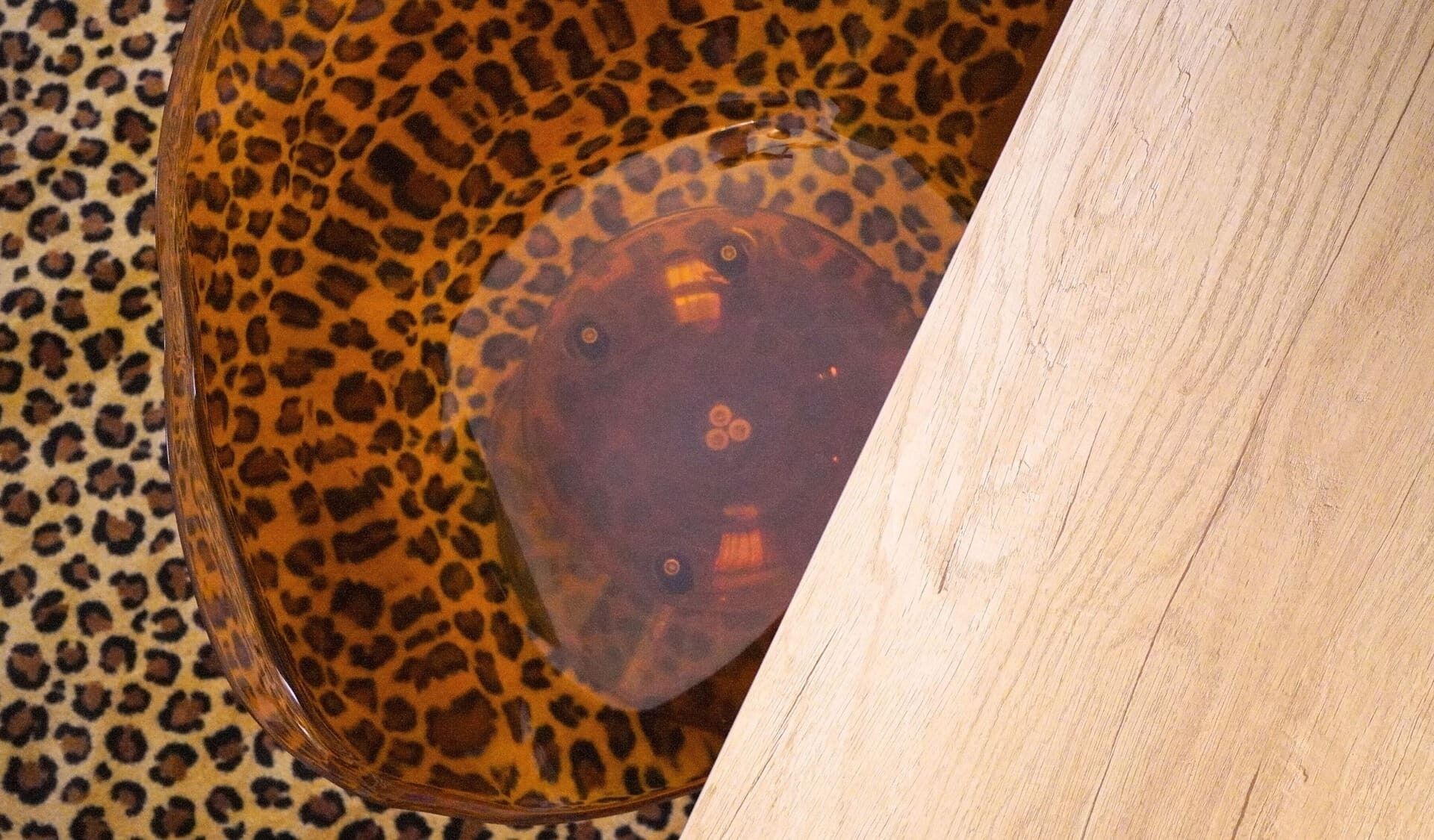 Eine Schüssel mit Leopardenmuster auf einer Holztischplatte.