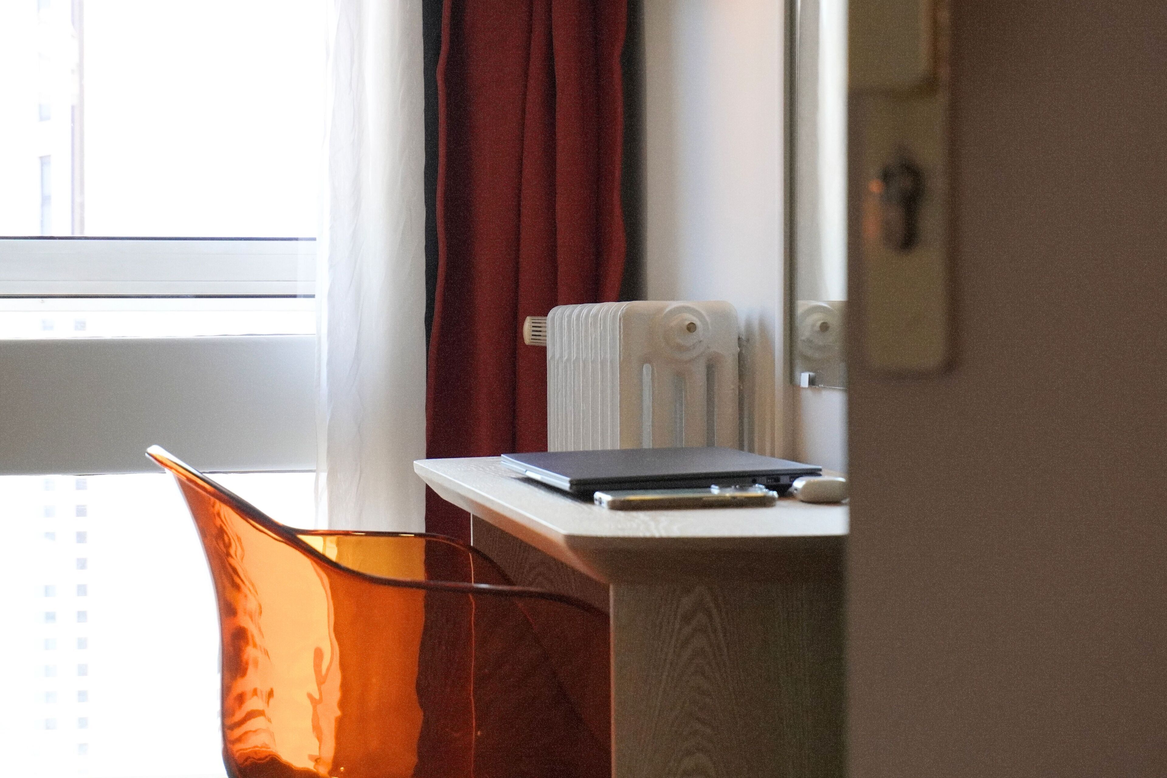 A room with a window, a radiator, a desk with a laptop, and a chair.