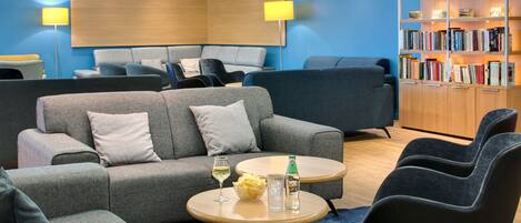 A modern lounge area with sofas, a coffee table, and a bookshelf.