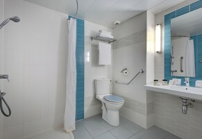 Casa de banho moderna com chuveiro, sanita e lavatório.